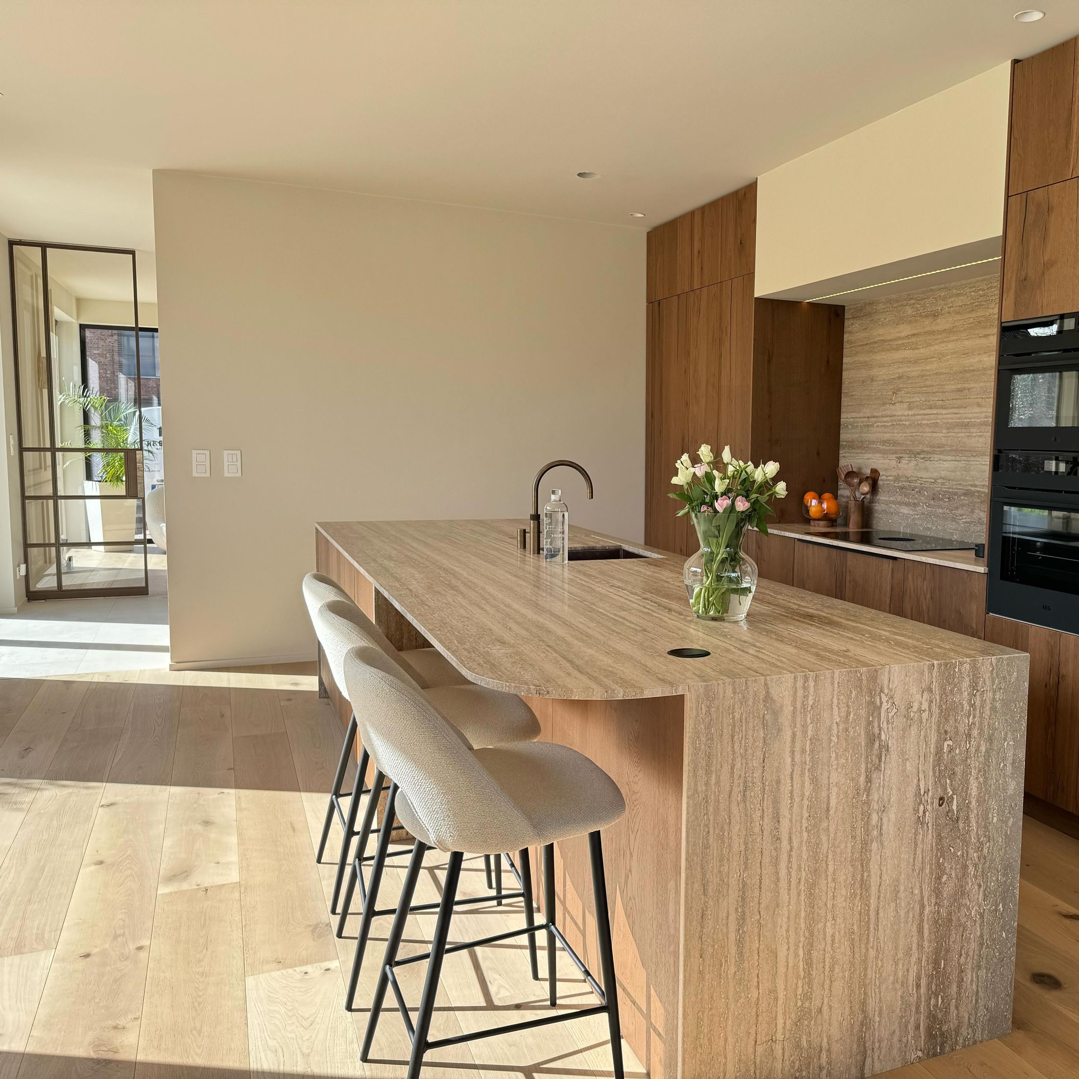 Keuken in eiken fineer met een eiland in Travertino Romano natuursteen