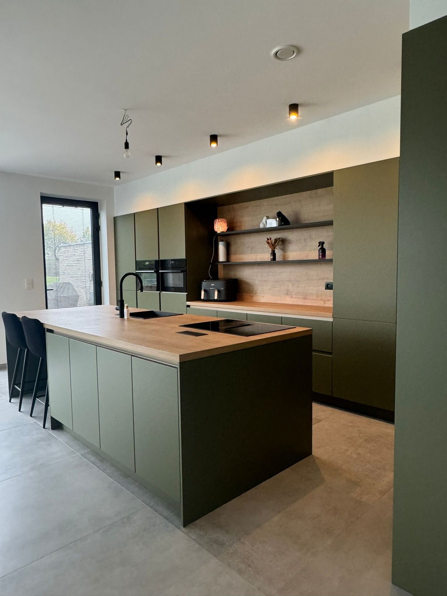 Olijfgroene keuken met warme houtaccenten en een hidden door